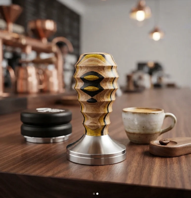 A sculpted wooden coffee tamper with a steel base beside a cup of coffee on a counter